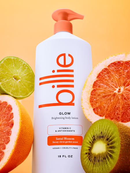 glow body lotion with oranges and kiwi on a yellow gradient background